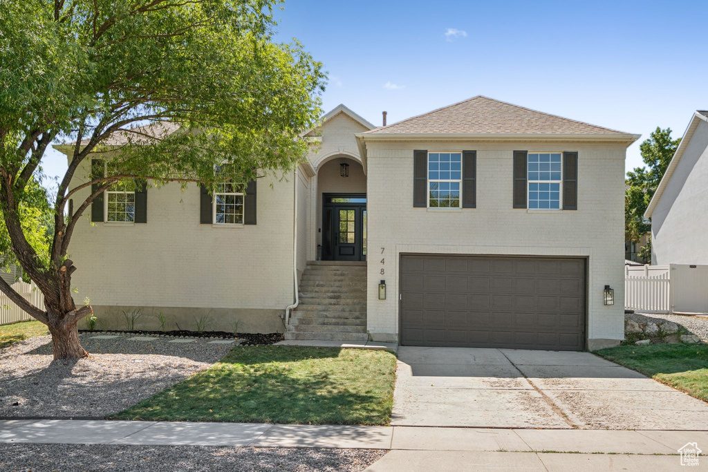 View of front of house with concrete driveway, a garage, and brick siding