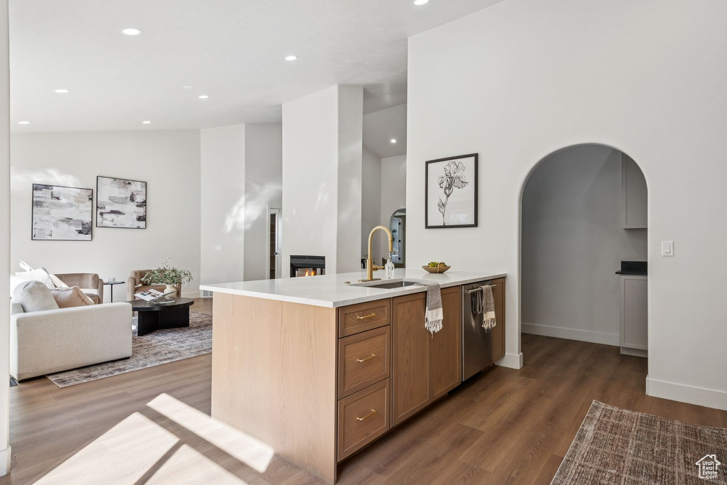 Kitchen featuring arched walkways, wood finished floors, light countertops, dishwasher, and recessed lighting