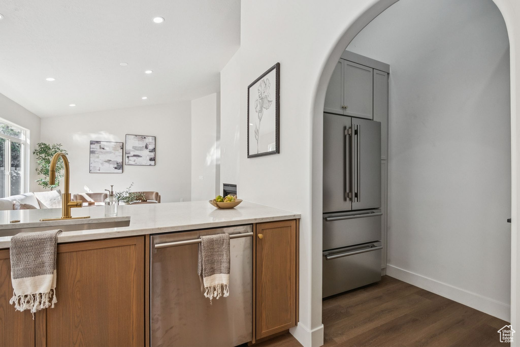 Kitchen featuring appliances with stainless steel finishes, arched walkways, recessed lighting, dark wood-style flooring, and light countertops