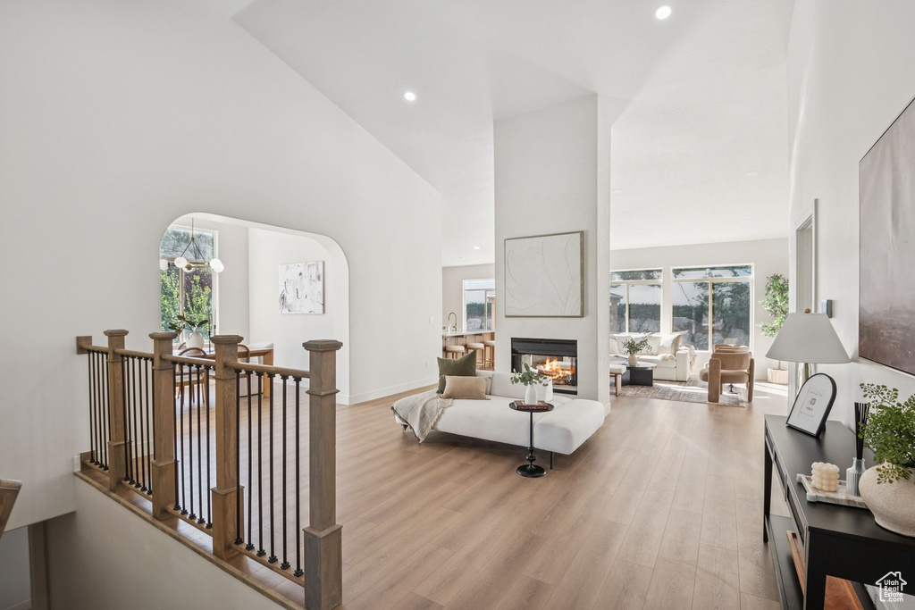 Living area with a high ceiling, plenty of natural light, light wood-style flooring, a multi sided fireplace, and recessed lighting