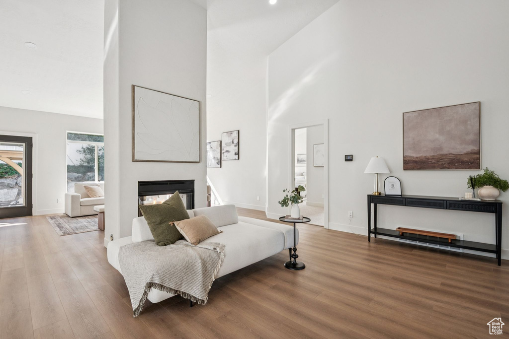 Living room with a high ceiling, wood finished floors, and a multi sided fireplace