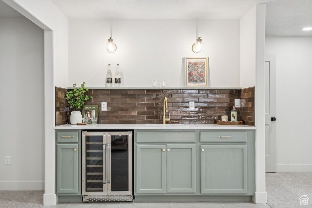 Indoor bar with beverage cooler, tasteful backsplash, and light carpet