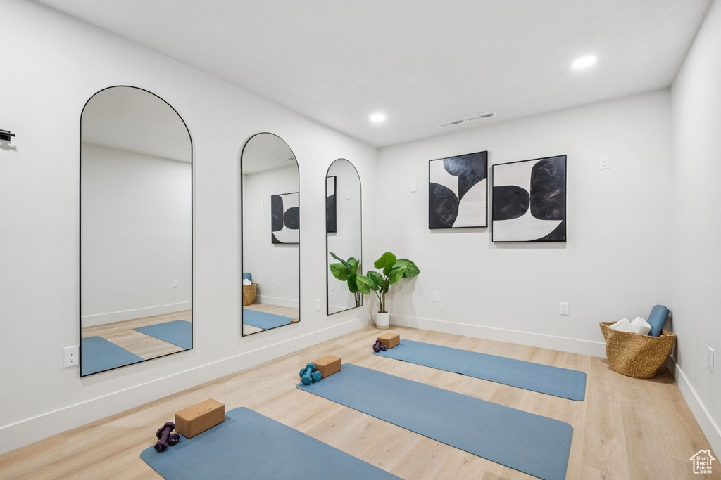 Exercise area with wood finished floors and recessed lighting