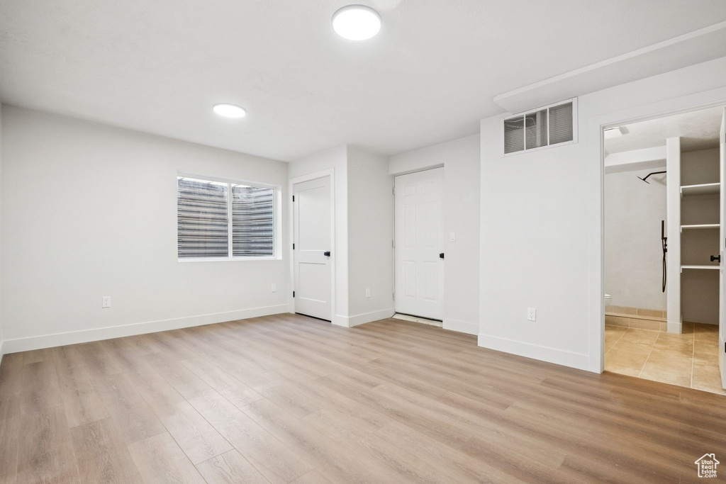 Unfurnished bedroom with light wood-style flooring and connected bathroom