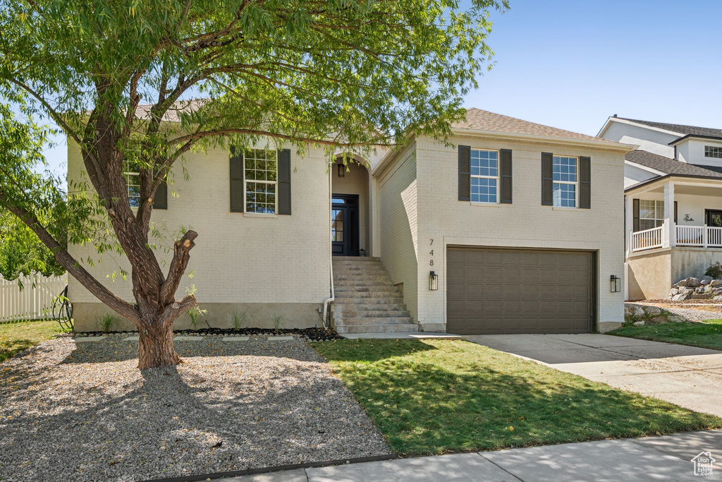 View of front of house with a garage, driveway, and brick siding
