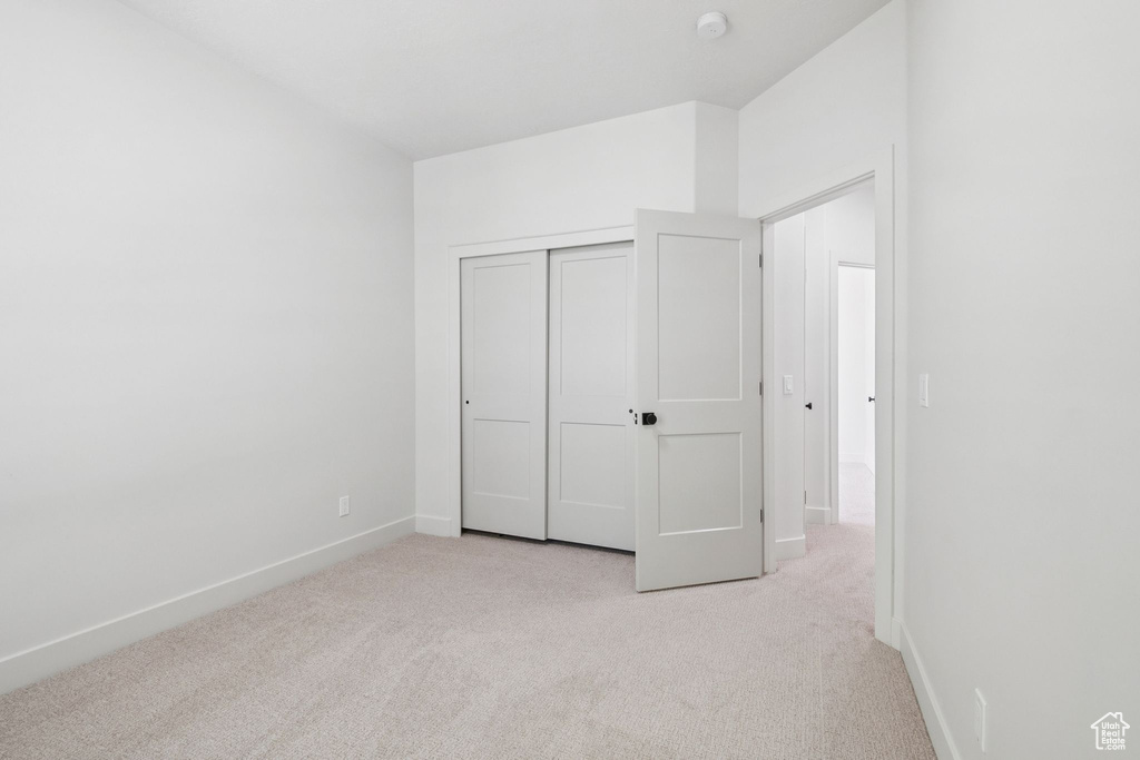 Unfurnished bedroom with light colored carpet and a closet