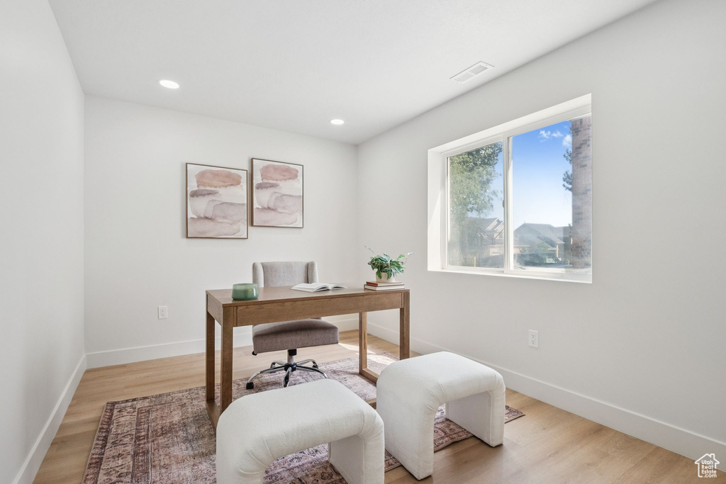 Office area with light wood-style floors and recessed lighting