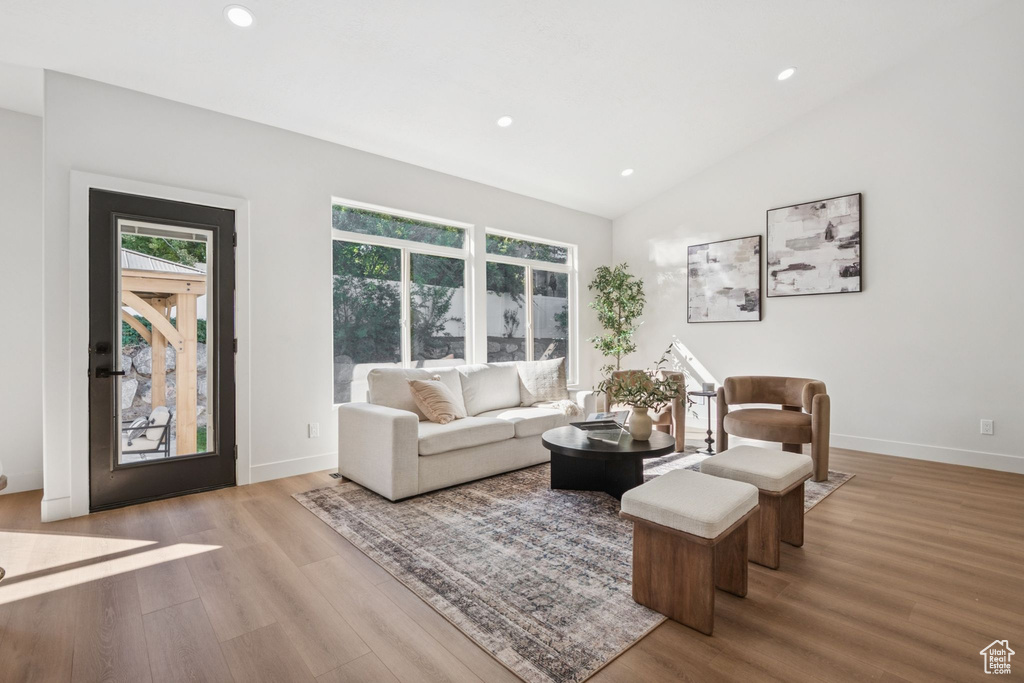 Living room with recessed lighting, wood finished floors, and lofted ceiling