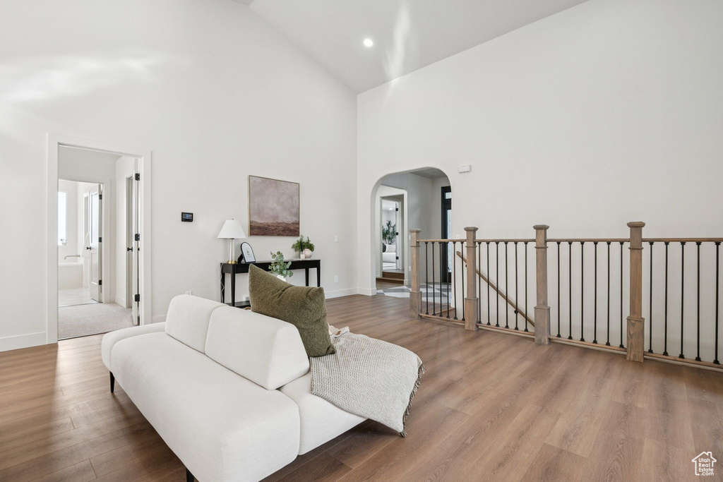 Living room featuring high vaulted ceiling, arched walkways, wood finished floors, and recessed lighting