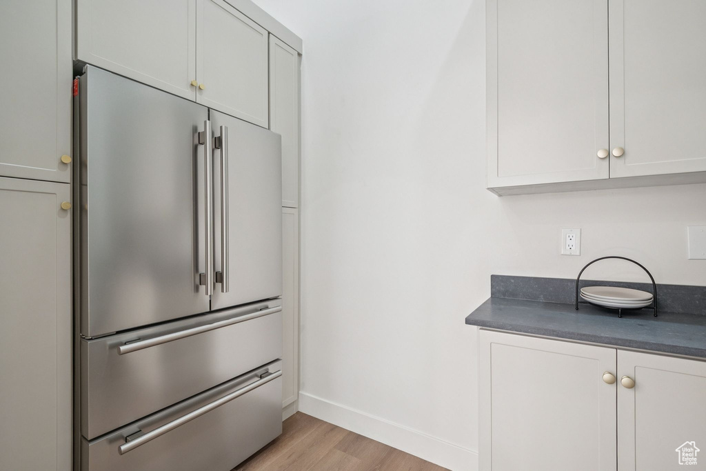 Kitchen with high quality fridge, dark countertops, light wood-style floors, and white cabinets