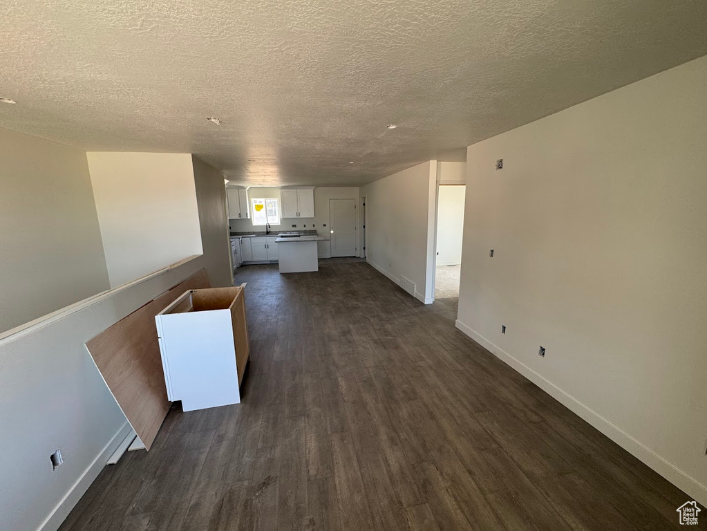 Unfurnished living room with dark wood-style flooring and a textured ceiling
