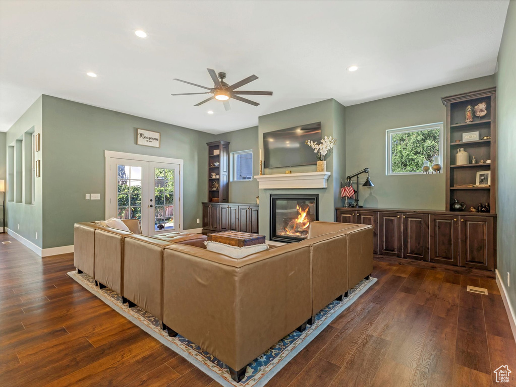 Living room featuring ceiling fan, dark wood-style flooring, a glass covered fireplace, recessed lighting, and healthy amount of natural light