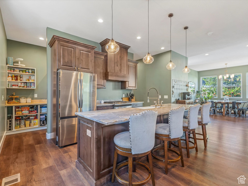 Kitchen featuring freestanding refrigerator, light stone countertops, dark wood-style flooring, pendant lighting, and recessed lighting