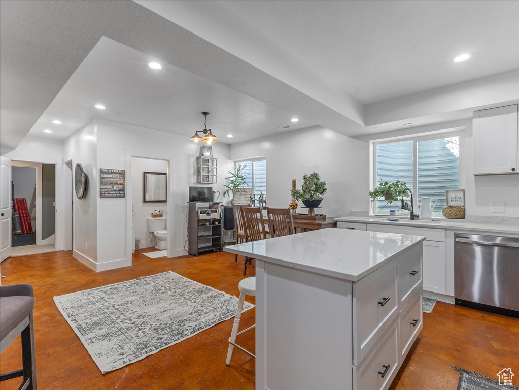 Kitchen with stainless steel dishwasher, a kitchen breakfast bar, recessed lighting, white cabinets, and a center island