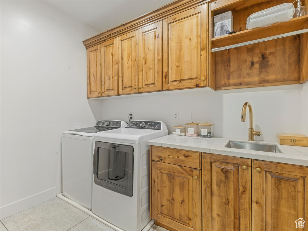Washroom with cabinet space, washing machine and dryer, and light tile patterned floors