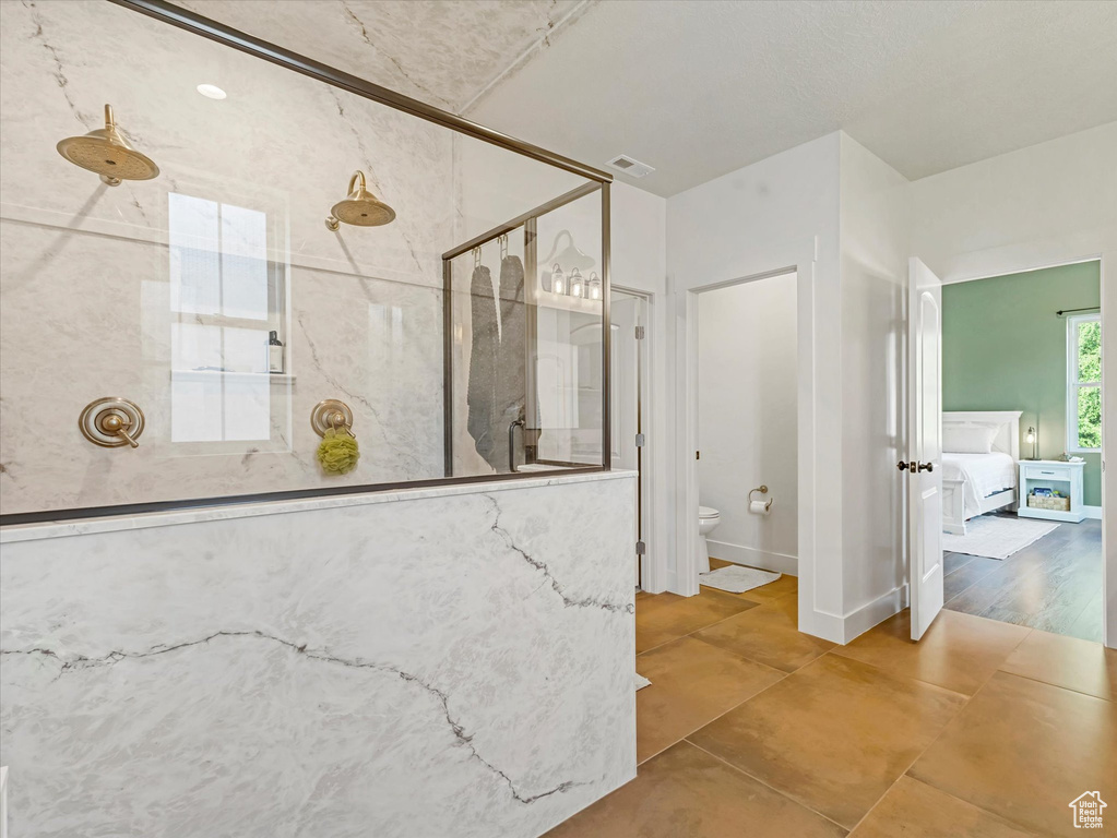 Full bathroom with a marble finish shower and tile patterned floors