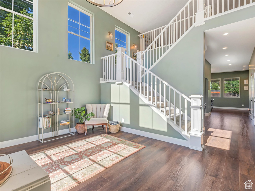 Living room featuring wood finished floors, stairway, recessed lighting, and a high ceiling