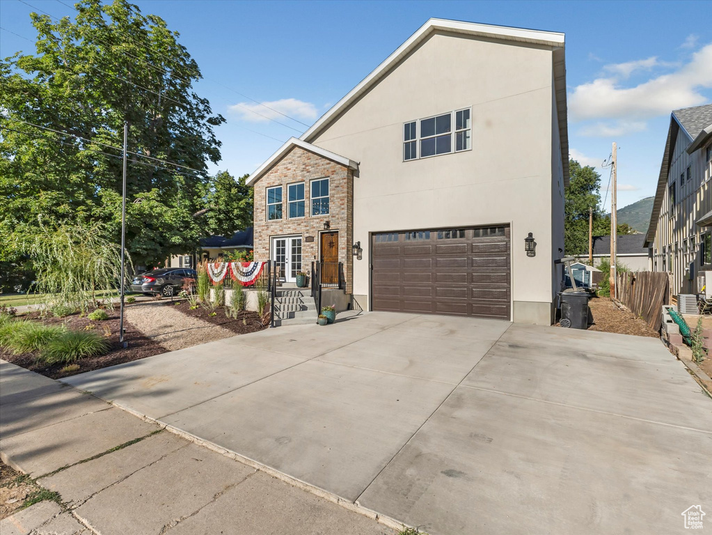Traditional-style home featuring stucco siding, a garage, and driveway