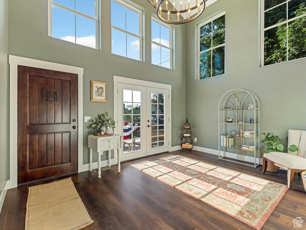 Foyer featuring plenty of natural light, dark wood finished floors, a chandelier, a high ceiling, and french doors