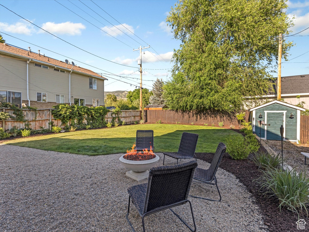 Fenced backyard featuring an outdoor fire pit and a shed