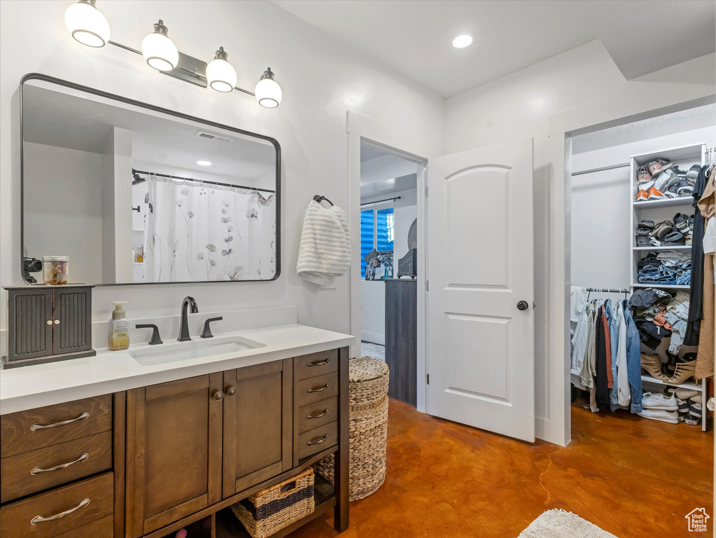 Bathroom featuring finished concrete floors, vanity, and a spacious closet