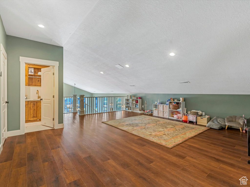 Interior space with wood finished floors, lofted ceiling, recessed lighting, and a textured ceiling