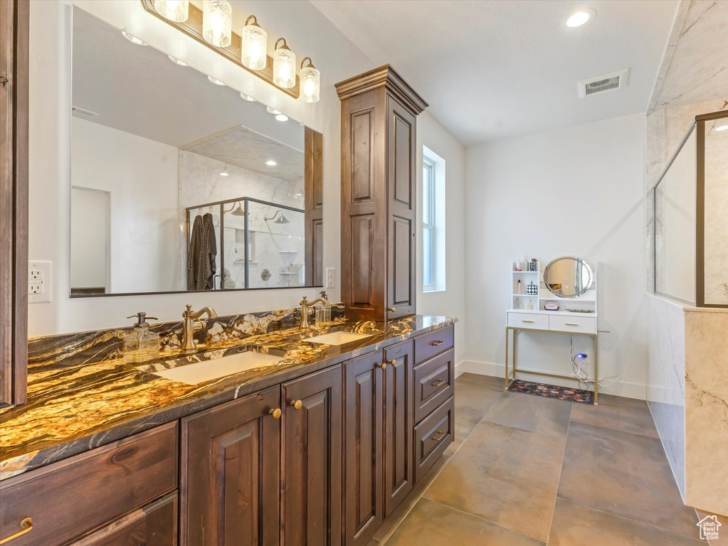 Bathroom with a marble finish shower, double vanity, and recessed lighting