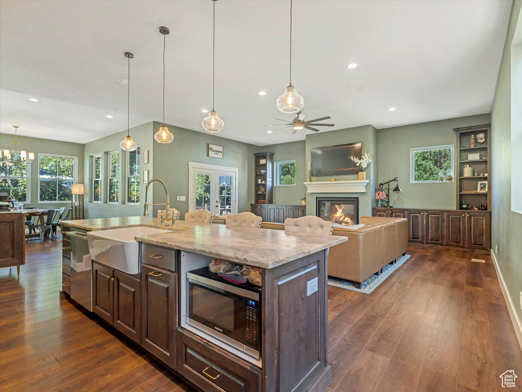 Kitchen with appliances with stainless steel finishes, recessed lighting, dark wood-style floors, a glass covered fireplace, and a ceiling fan