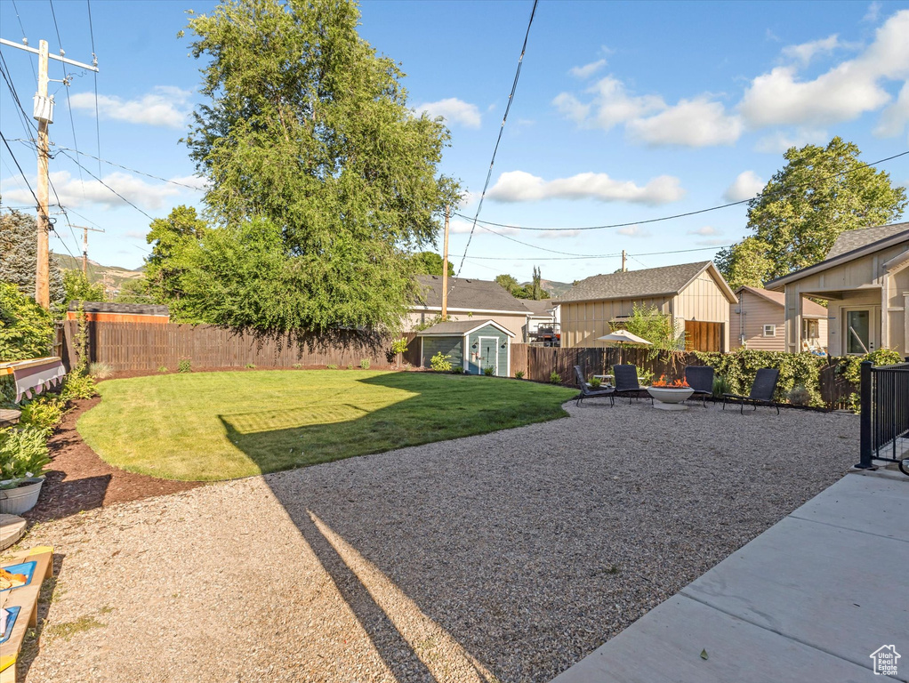 Fenced backyard featuring a shed, a patio, and an outdoor fire pit