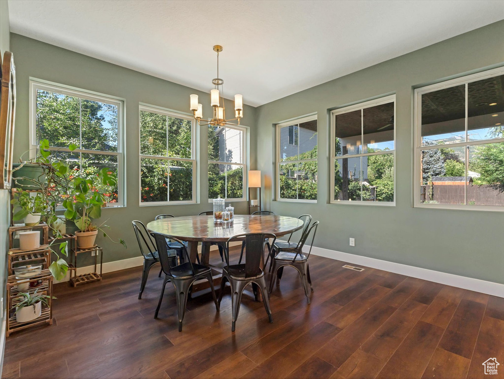 Dining room with a chandelier, plenty of natural light, and dark wood-type flooring