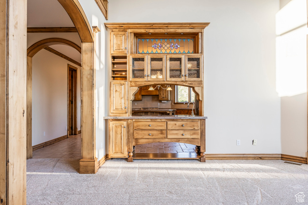 Bar area featuring carpet, arched walkways, and backsplash