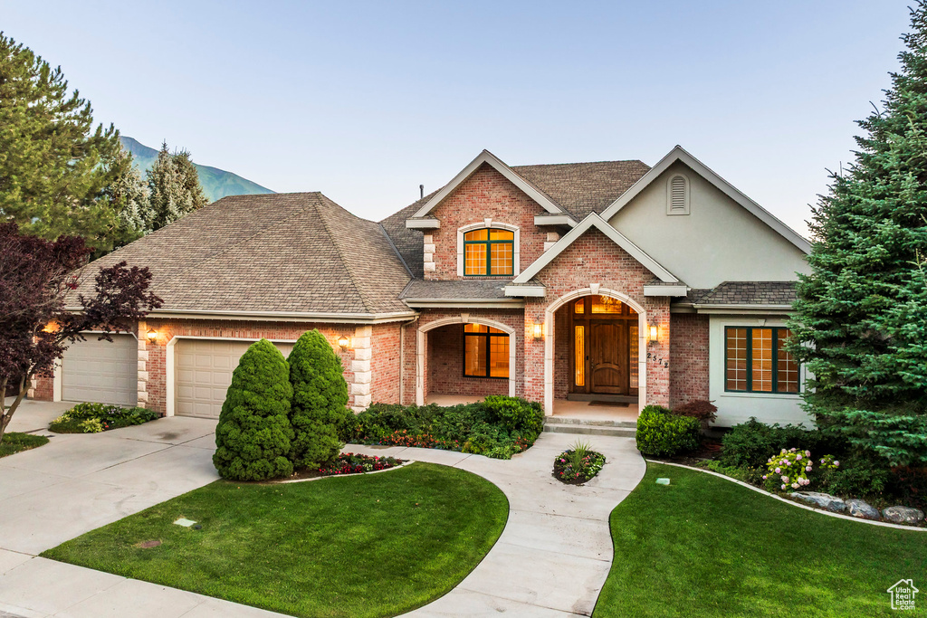 Craftsman inspired home featuring driveway, brick siding, a front lawn, a garage, and roof with shingles
