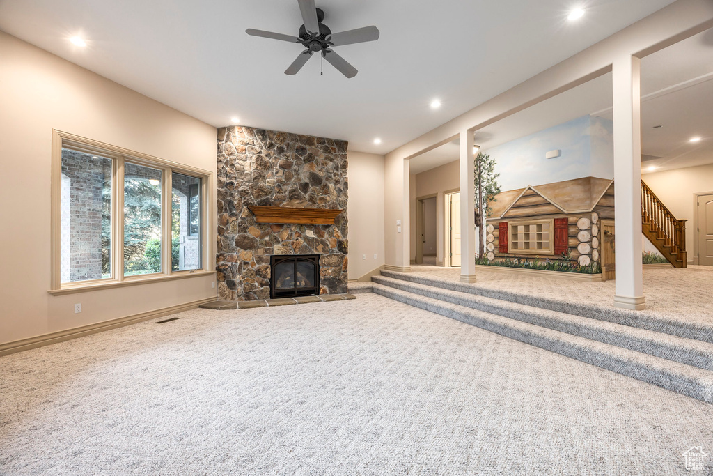Unfurnished living room featuring a stone fireplace, carpet floors, ceiling fan, stairway, and recessed lighting
