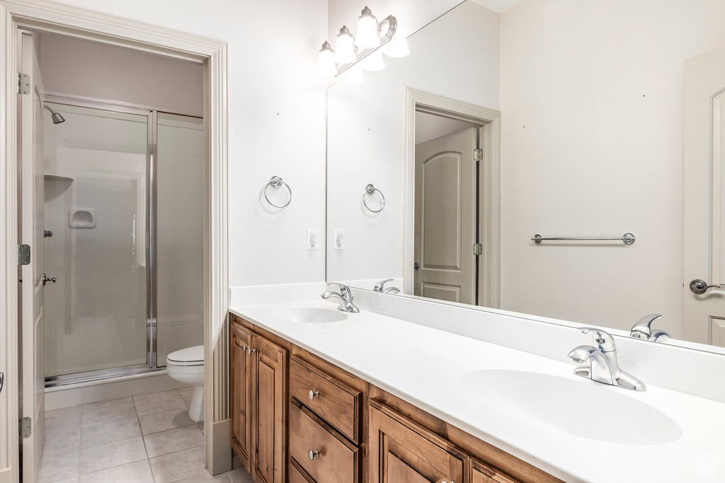 Full bath with a shower stall, double vanity, and tile patterned floors