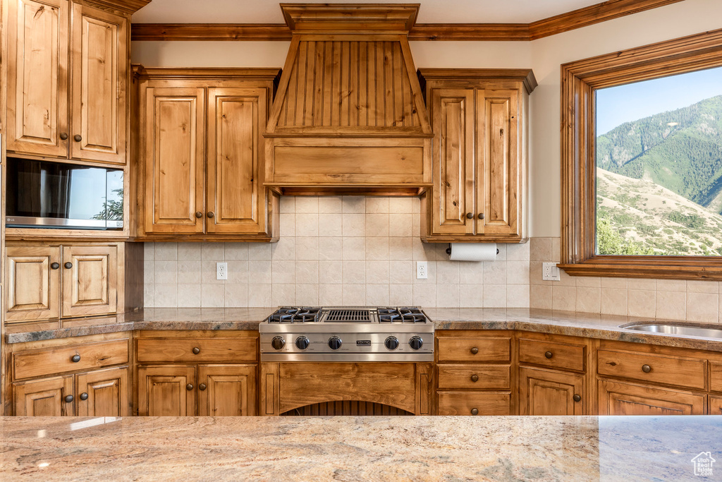 Kitchen with ornamental molding, custom exhaust hood, stainless steel gas cooktop, backsplash, and a mountain view