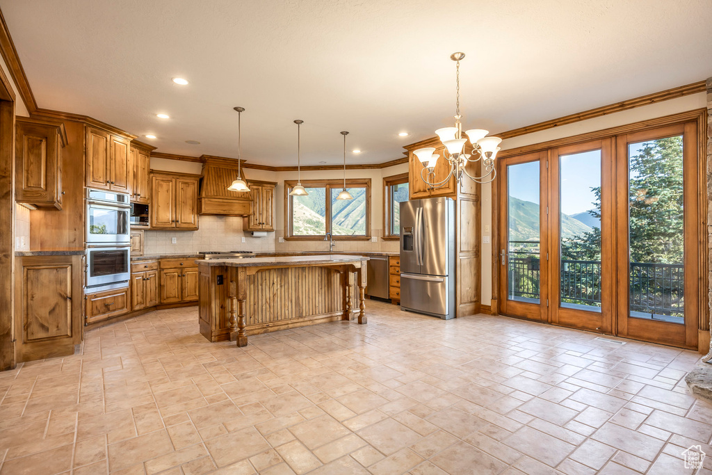 Kitchen featuring brown cabinetry, backsplash, appliances with stainless steel finishes, a kitchen breakfast bar, and stone tile flooring