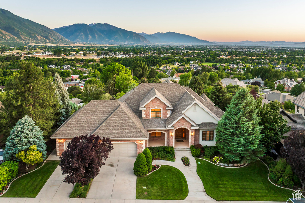 View of front facade featuring brick siding, a mountain view, an attached garage, concrete driveway, and roof with shingles