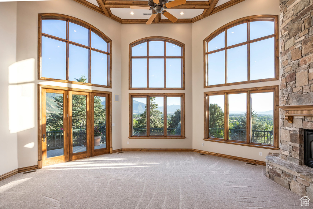 Unfurnished living room with carpet, a fireplace, recessed lighting, a high ceiling, and a ceiling fan