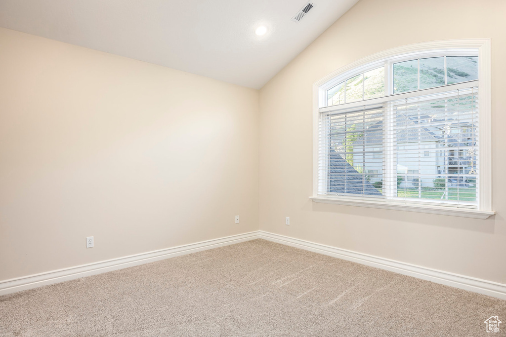 Carpeted empty room with lofted ceiling and recessed lighting