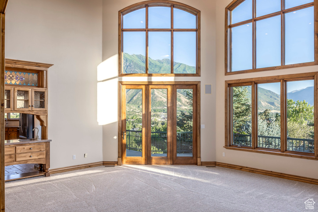 Unfurnished living room featuring a towering ceiling, carpet flooring, and a mountain view