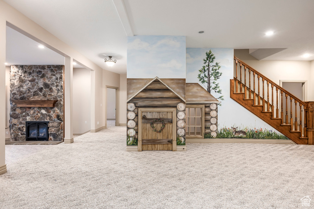 Unfurnished living room featuring carpet, a stone fireplace, stairs, and recessed lighting
