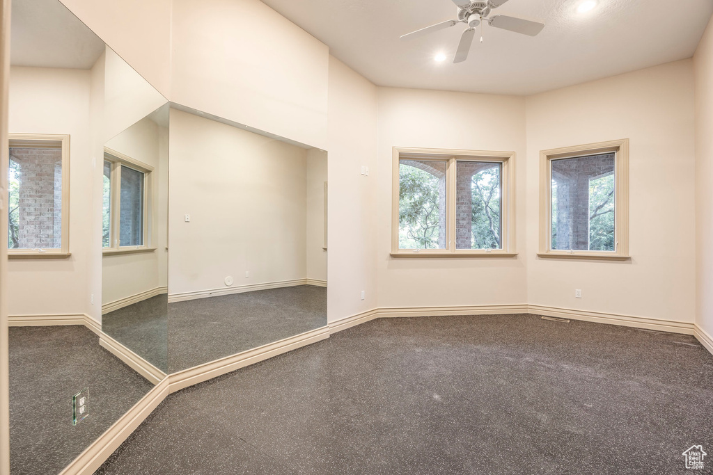 Carpeted spare room with a ceiling fan and baseboards