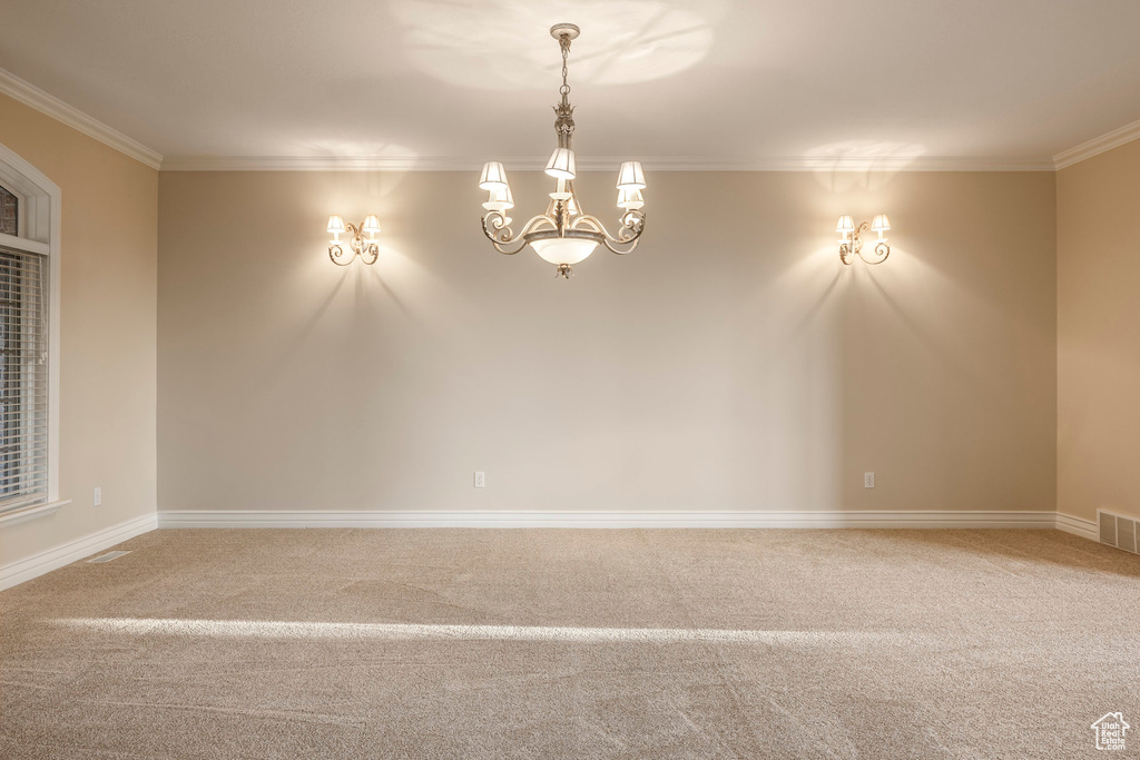 Spare room featuring crown molding, a chandelier, and carpet flooring