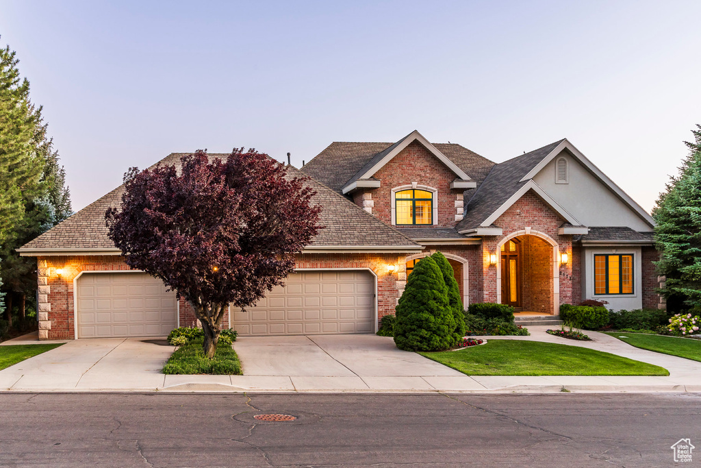 View of front of home with brick siding, driveway, and roof with shingles
