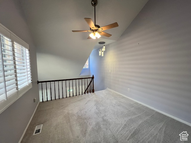 Empty room featuring vaulted ceiling, a ceiling fan, and carpet floors