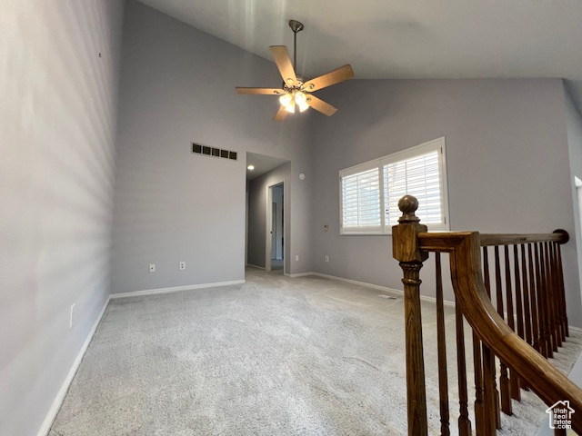 Empty room with vaulted ceiling, a ceiling fan, and light colored carpet