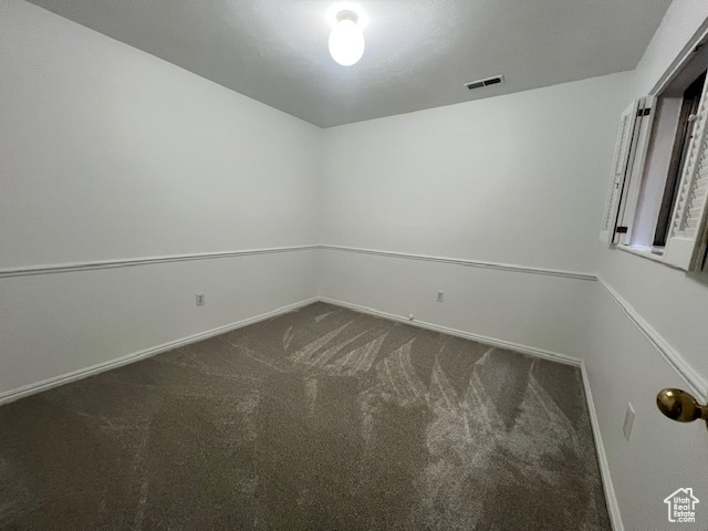 Carpeted spare room featuring baseboards