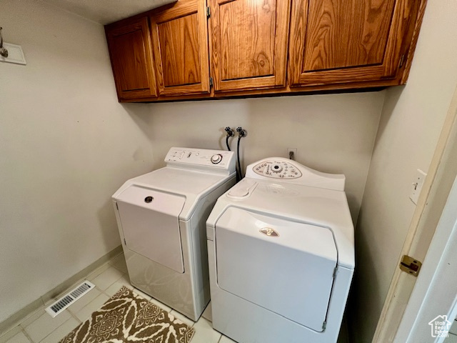 Laundry area featuring cabinet space, light tile patterned floors, and washer and clothes dryer