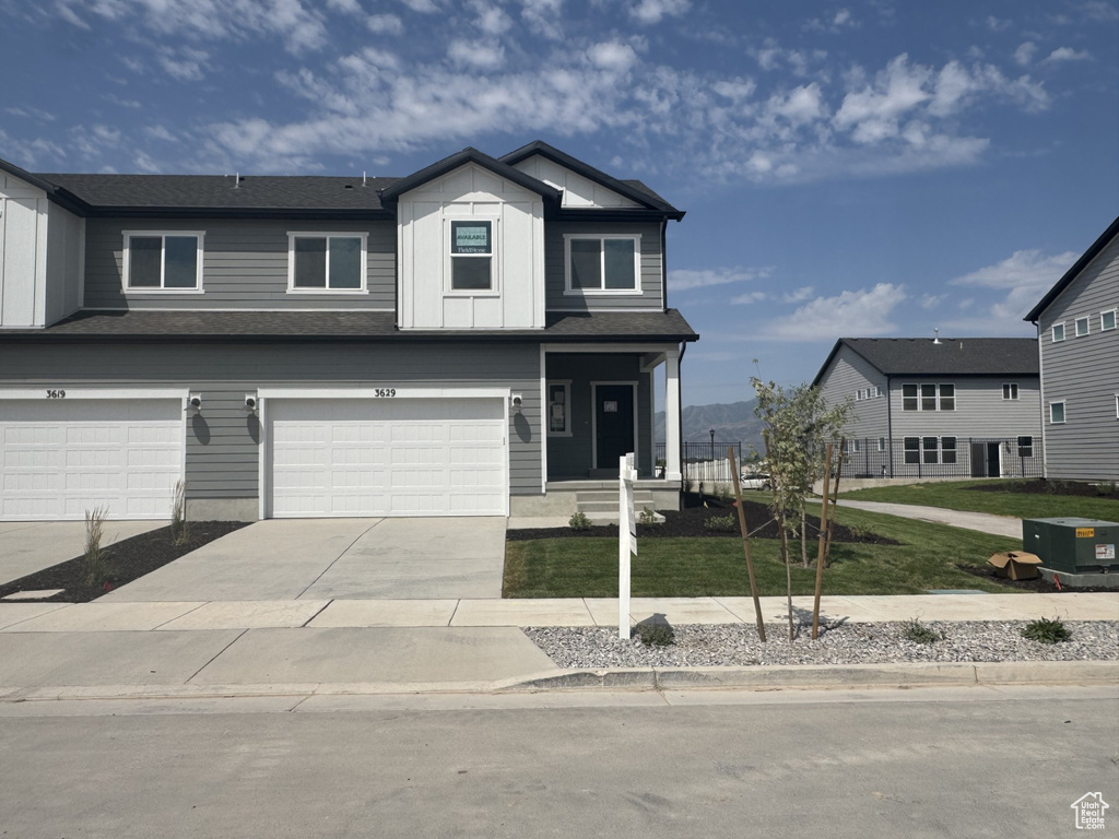 View of front of property featuring concrete driveway, an attached garage, and a front lawn