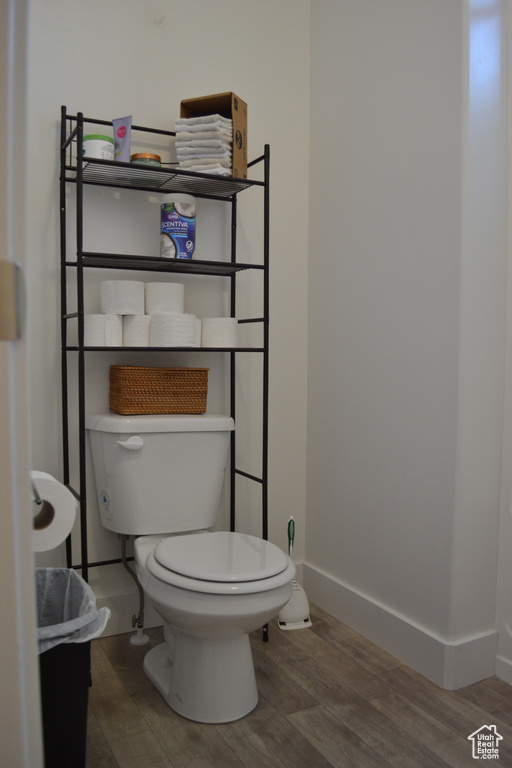 Half bathroom featuring toilet and wood finished floors